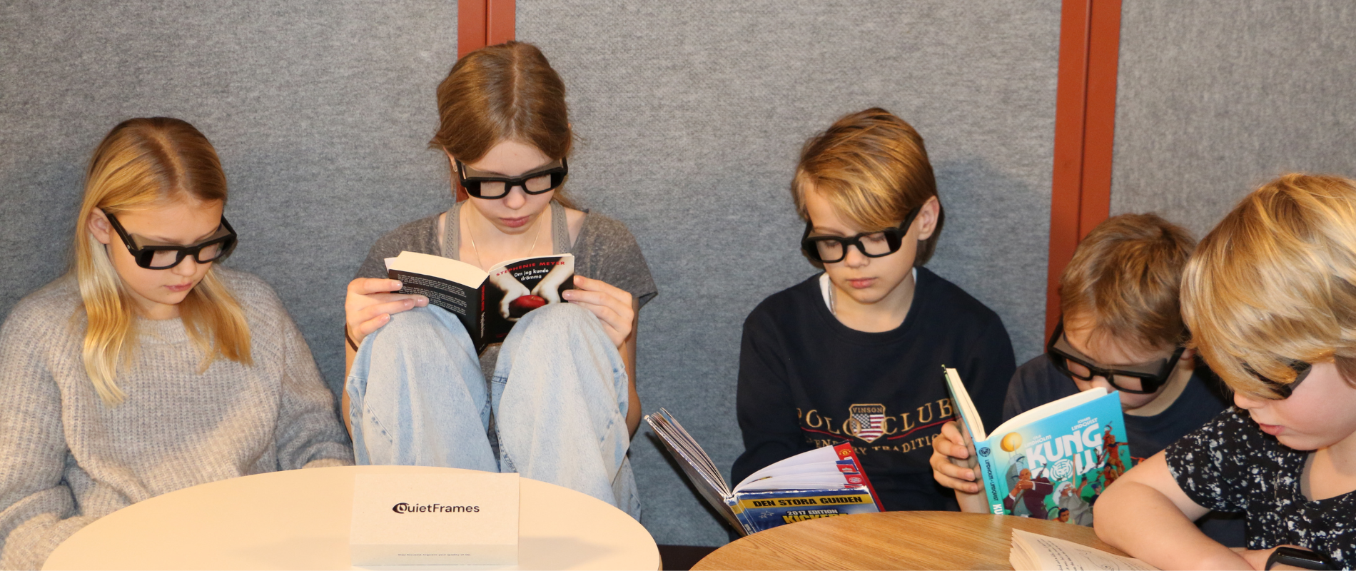 Grupp elever sitter och läser med sina QuietFrames brusreducerande glasögon.